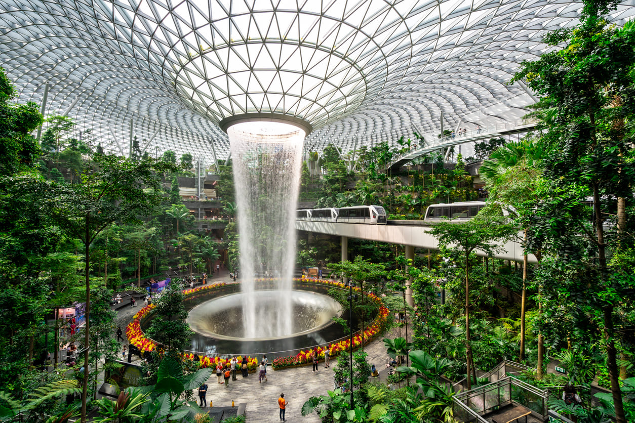 The Jewel at Singapore Changi Airport showcases the breathtaking Rain Vortex, surrounded by vibrant greenery and modern architecture.