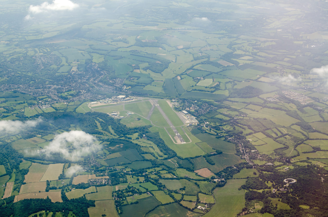 An aerial view of London Biggin Hill Airport nestled amidst rolling green fields and nearby towns.