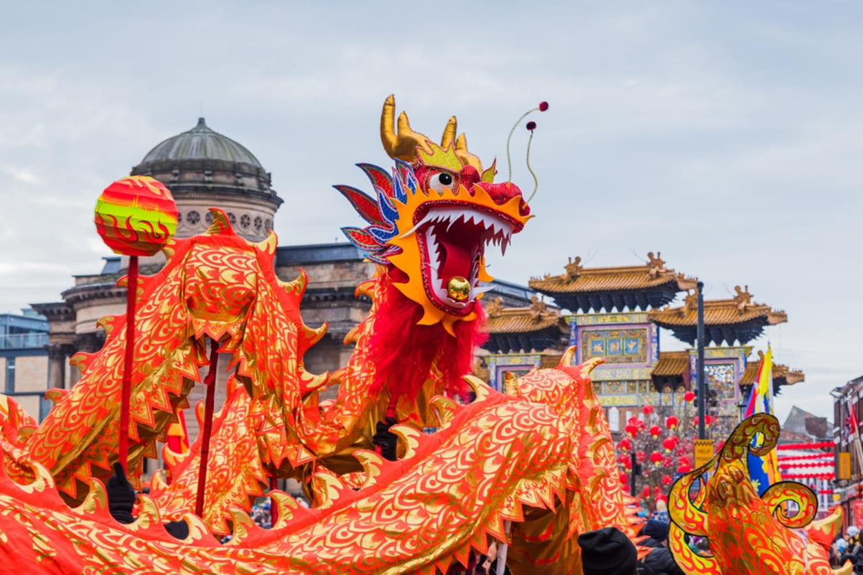 Performers in a colorful dragon dance, surrounded by festive decorations and a lively crowd celebrating the Lunar New Year.