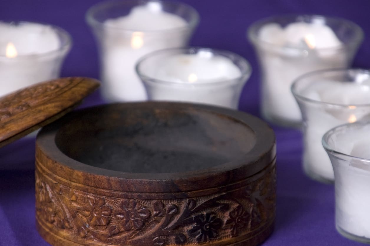 A carved wooden bowl containing ashes, surrounded by soft candlelight, symbolizing the reflective and spiritual tone of Ash Wednesday.