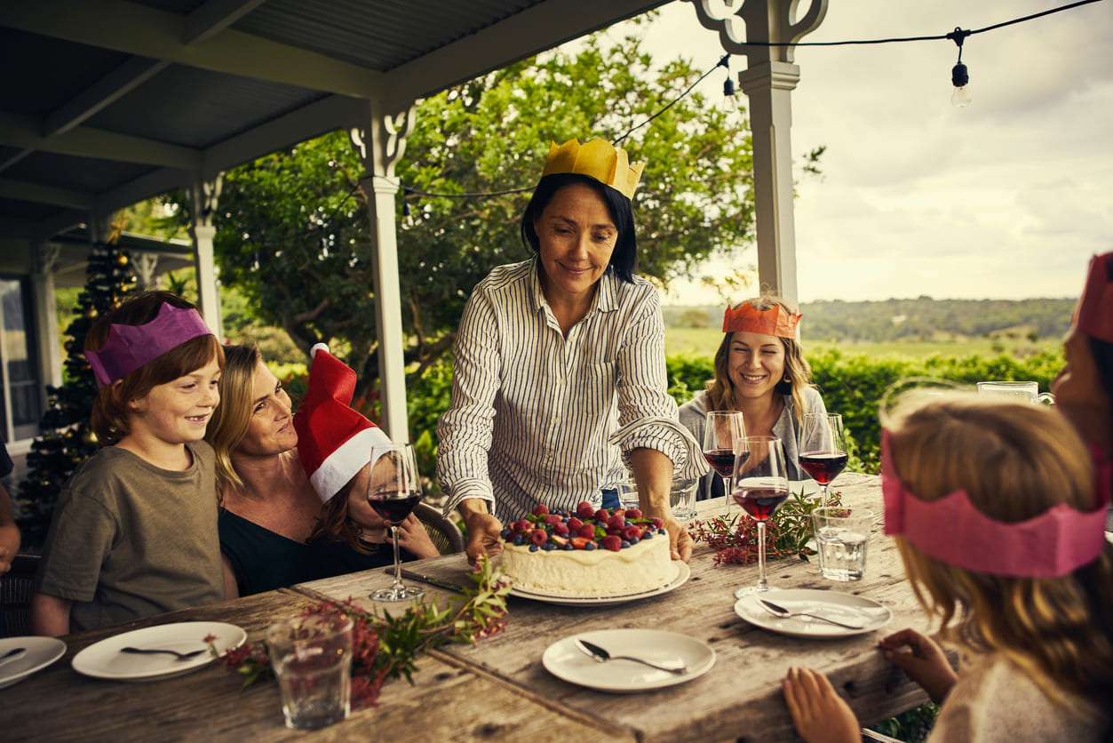 An Australian family gathers outdoors on Christmas Day, sharing a festive meal with paper crowns, summer treats, and joyful celebrations.