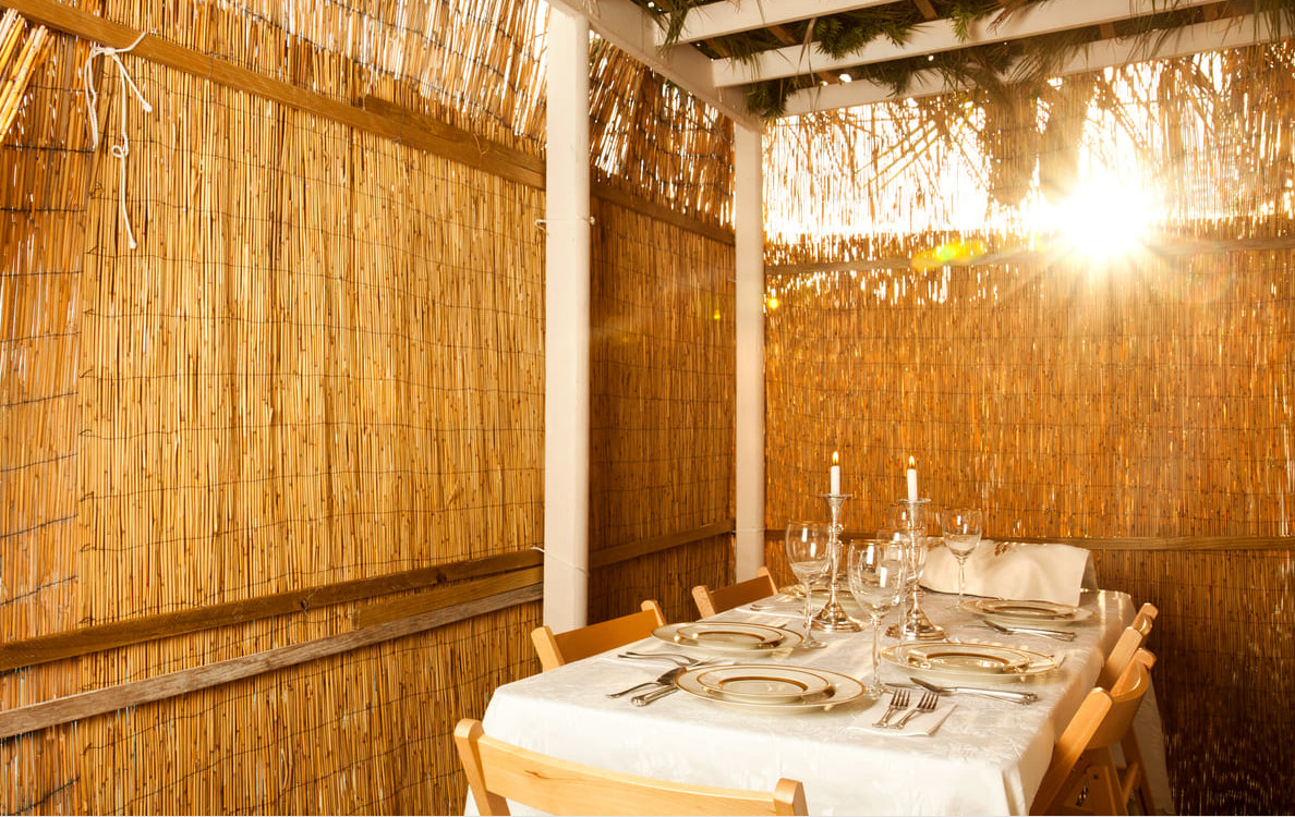A cozy, sunlit sukkah with a beautifully set table, ready for a festive Sukkot celebration.