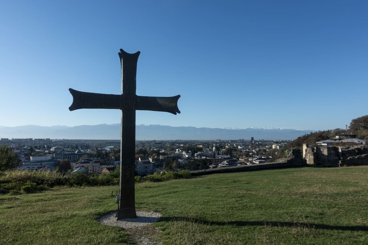 A large cross stands atop a hill, overlooking a city and symbolizing faith, sacrifice, and reflection.
