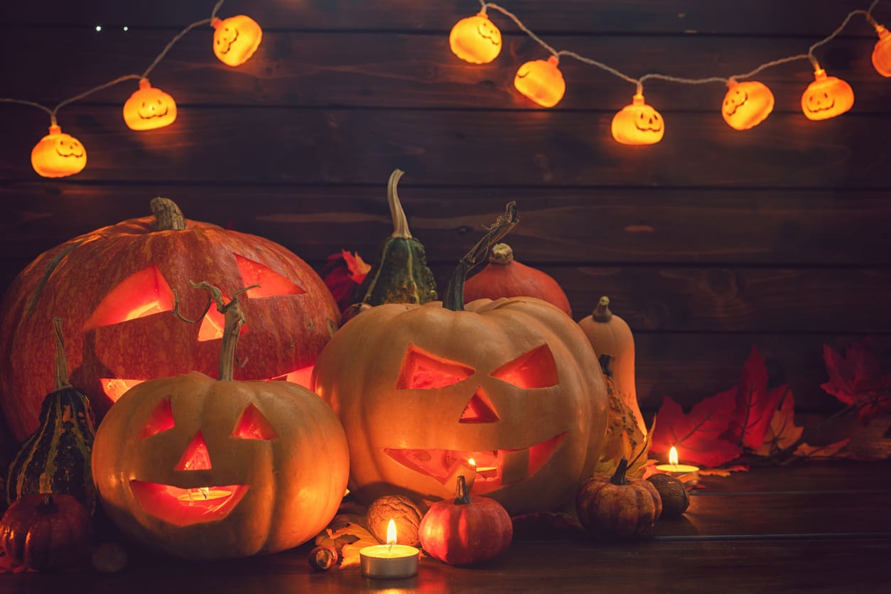 A festive Halloween scene with glowing jack-o'-lanterns, candlelight, and autumn-themed decorations creating a spooky atmosphere.