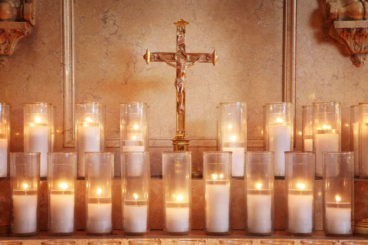 A golden crucifix stands among glowing candles, symbolizing prayer, reflection, and anticipation on Holy Saturday.
