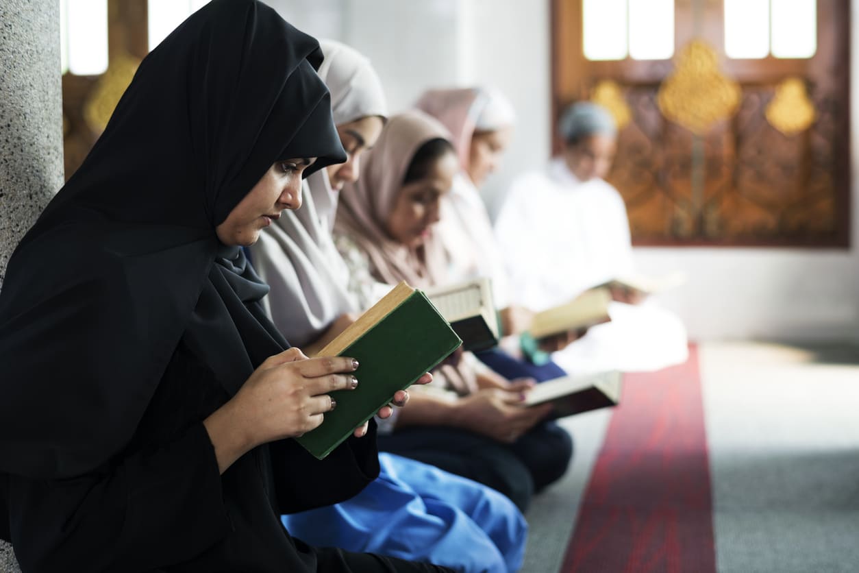 A group of women seated in a mosque, quietly reading the Quran in deep reflection and devotion.