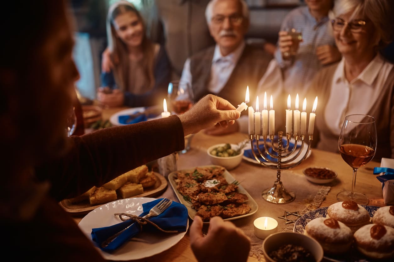 A warm family setting features a festive meal and a fully lit menorah, capturing the spirit and tradition of the last day of Hanukkah.