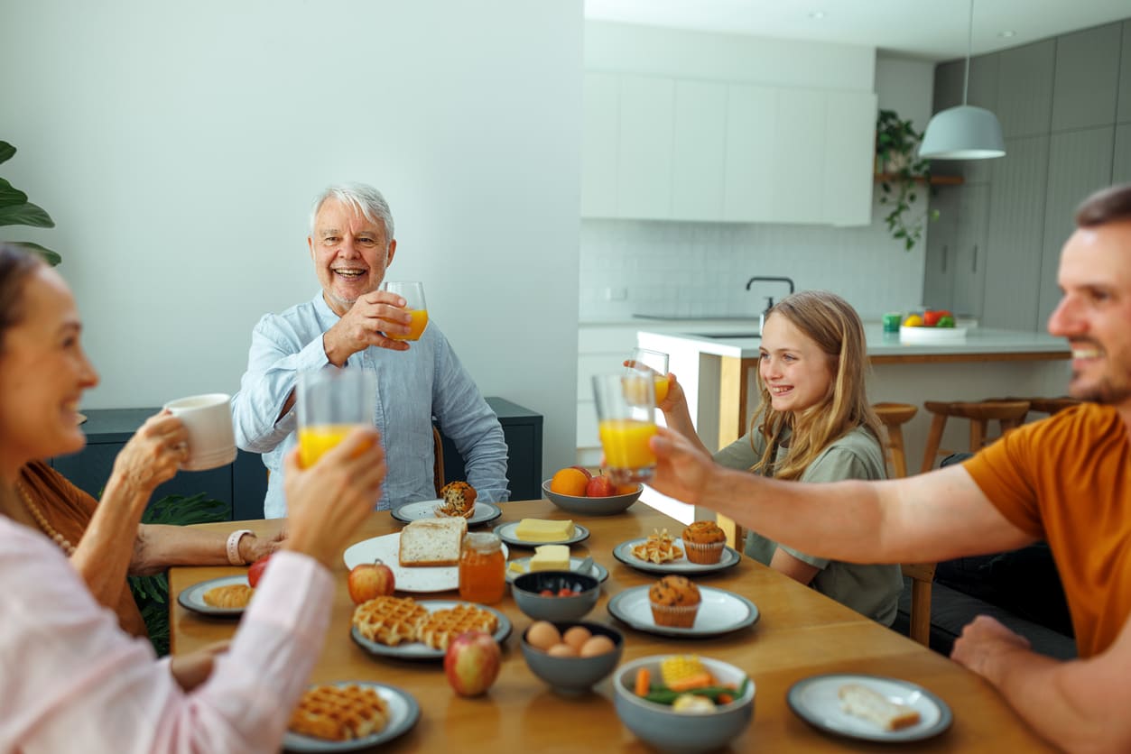 A cheerful family gathered around the breakfast table, sharing drinks and enjoying each other's company.