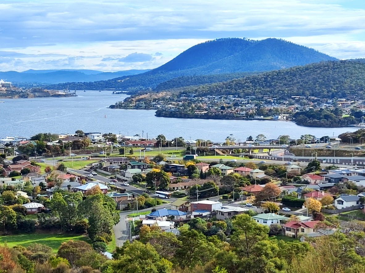 A peaceful suburban landscape in northern Tasmania, with homes nestled near the river and surrounded by rolling hills.