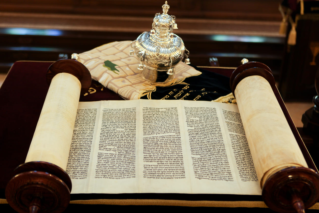 An open Torah scroll rests on a velvet-covered table, ready for reading in a synagogue during Simchat Torah.