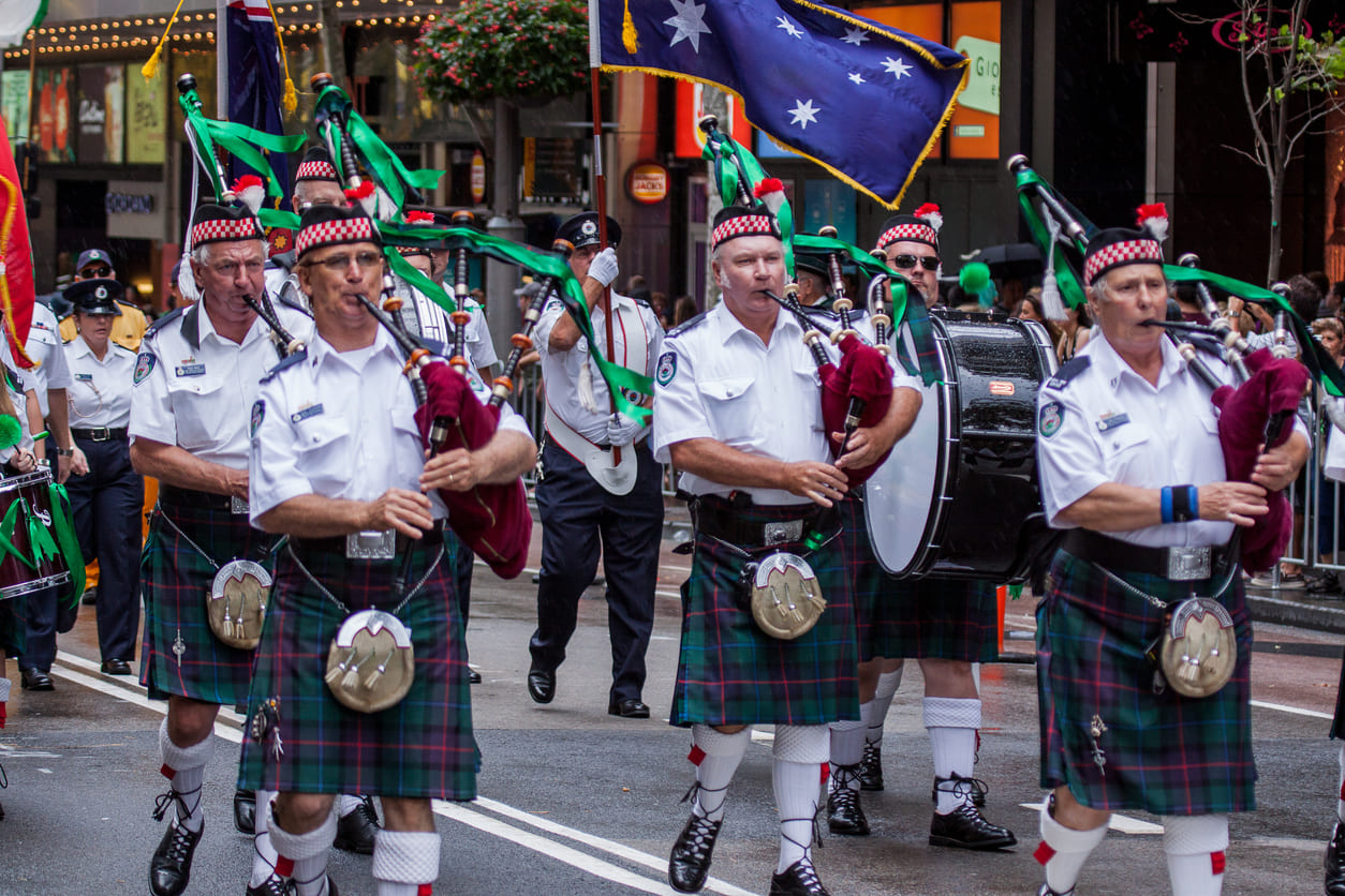 A lively St. Patrick's Day parade in Sydney, with uniformed bagpipers in kilts marching through the streets amid festive crowds.
