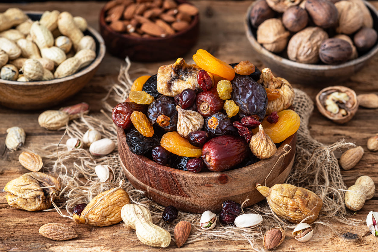 A rustic wooden table displays bowls overflowing with dried fruits and nuts, capturing the earthy, festive spirit of Tu B'Shevat.