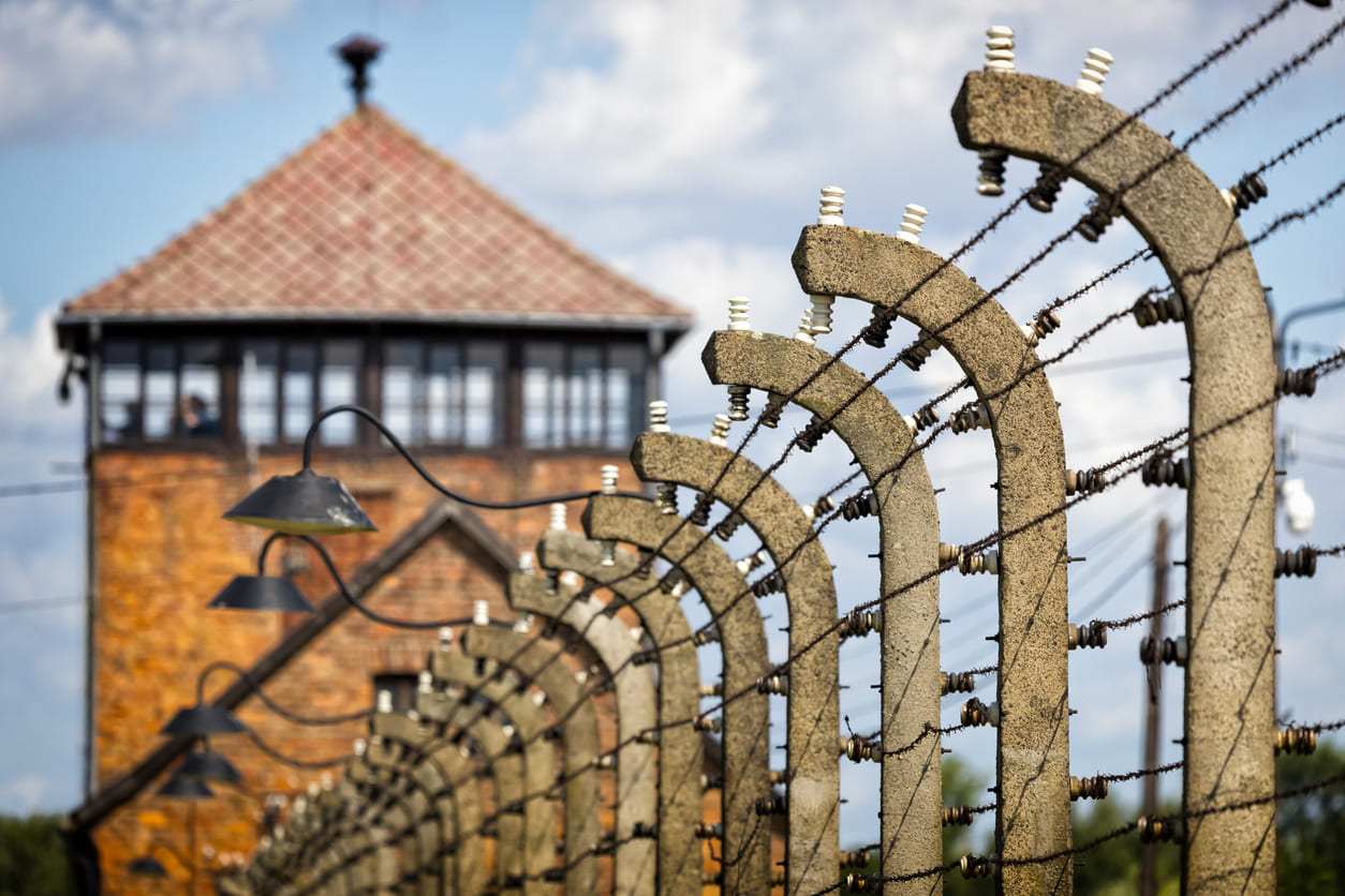 A row of barbed wire fences leads to the guard tower at Auschwitz, capturing the haunting atmosphere of the former concentration camp.