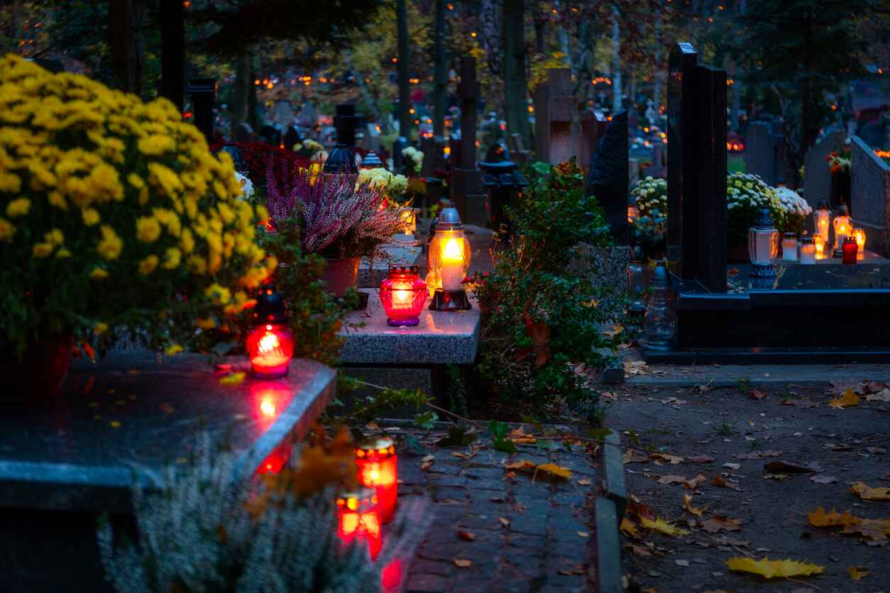 A serene cemetery scene on All Saints' Day, with glowing candles and vibrant chrysanthemums placed in remembrance of loved ones.