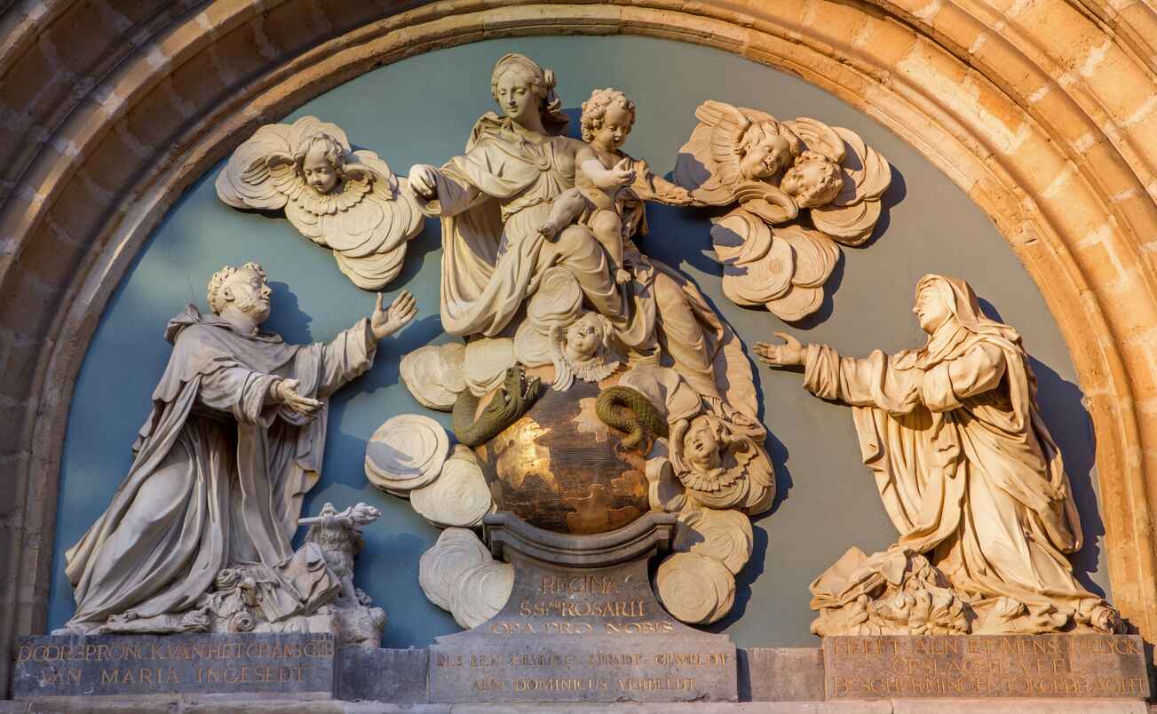 A detailed religious sculpture depicting the Virgin Mary and child surrounded by angels and worshippers, symbolizing faith and devotion.