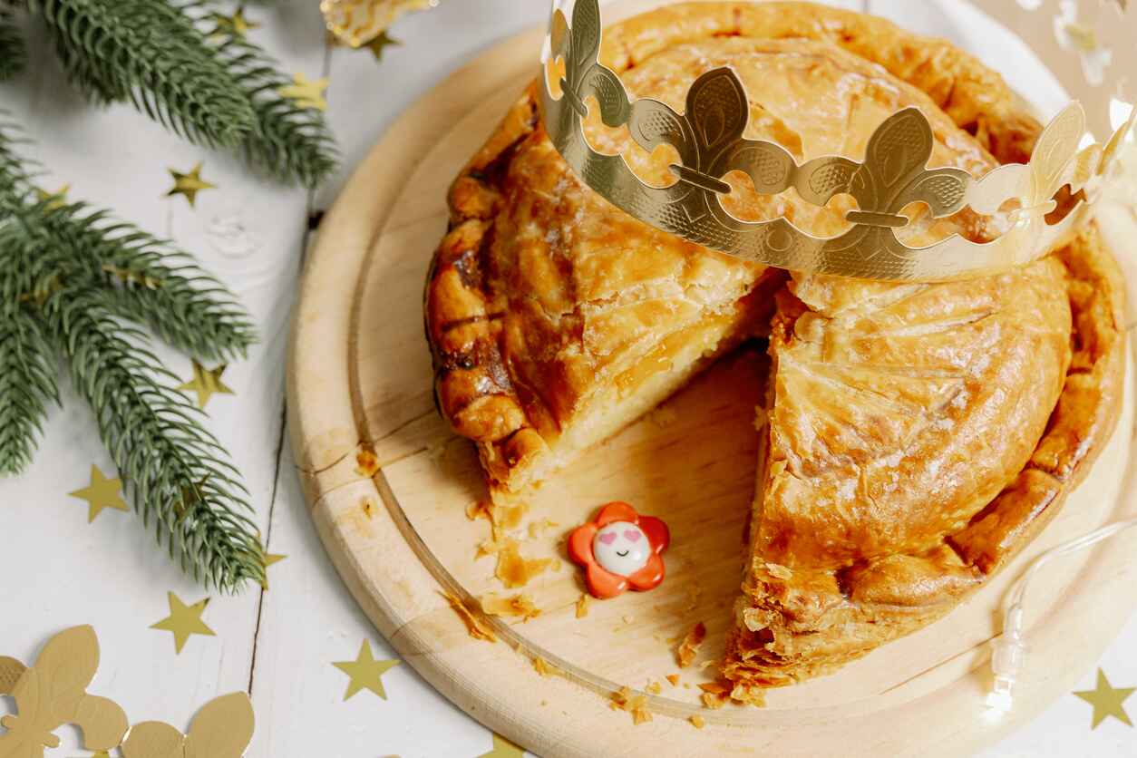 A golden Galette des Rois with a festive crown and hidden charm, celebrating Epiphany traditions in Belgium.