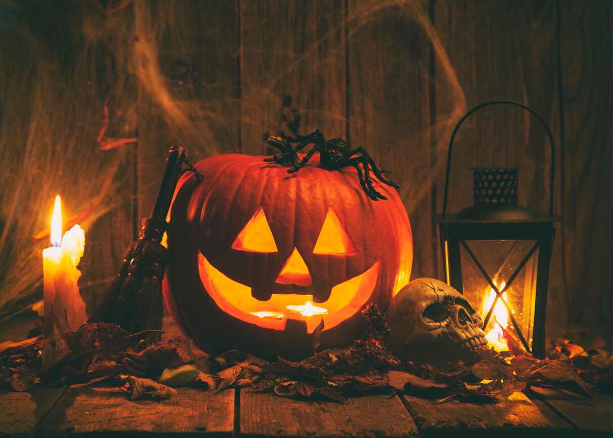 A glowing jack-o'-lantern with a spooky spider, candle, skull, and lantern, creating a classic eerie Halloween atmosphere.