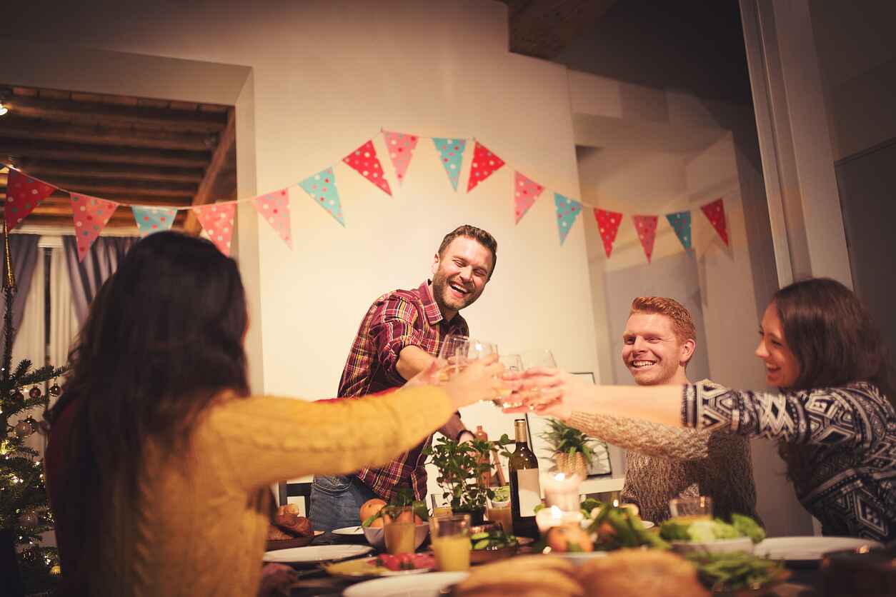 A warm and festive New Year's Eve gathering where friends toast with drinks, sharing laughter and joy around a decorated dinner table.