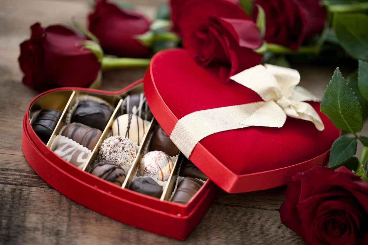 A heart-shaped box of luxurious Belgian chocolates paired with red roses, capturing the essence of love and romance on Valentine's Day.