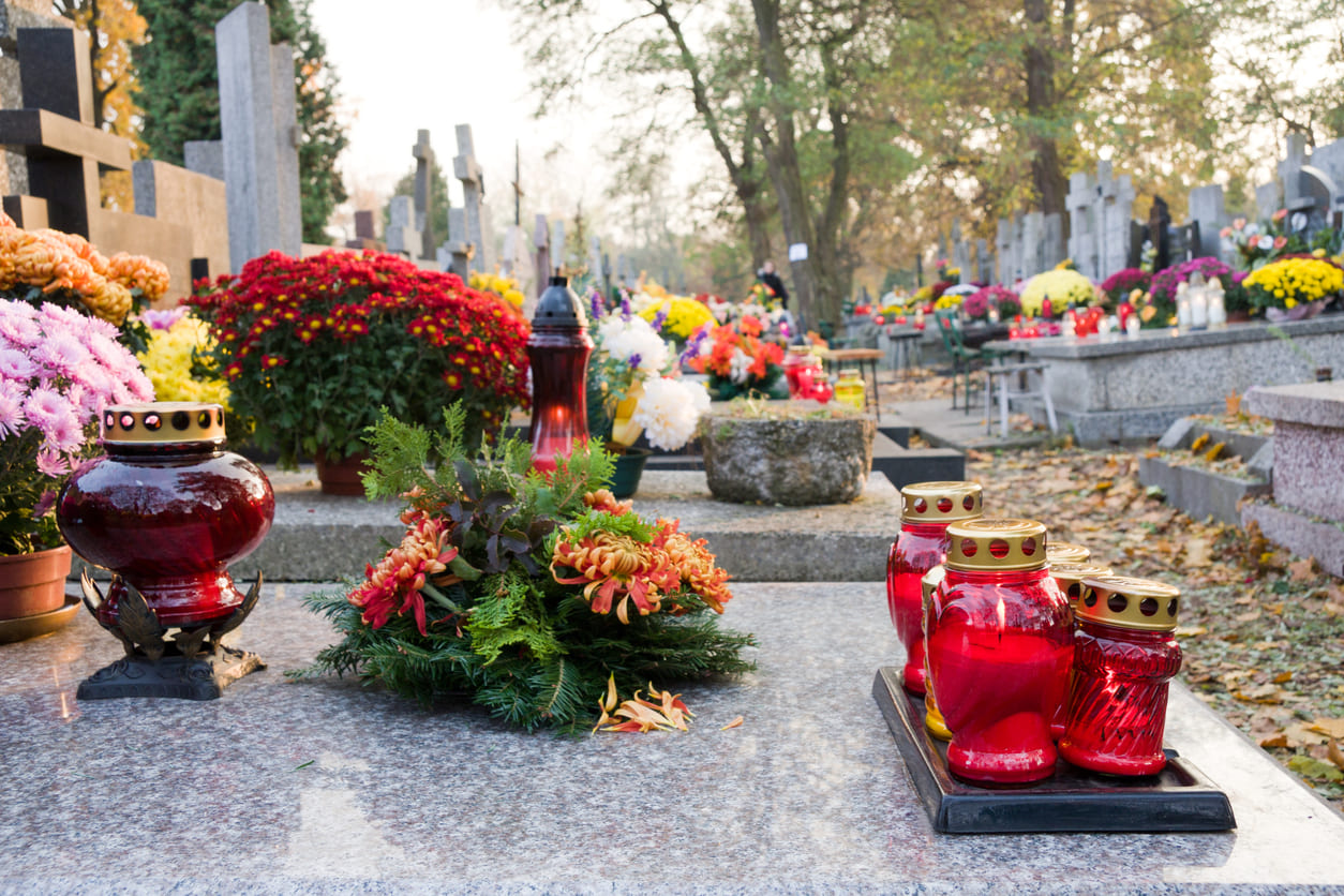 A peaceful cemetery filled with colorful flowers and glowing candles placed on graves, creating a serene atmosphere of remembrance.