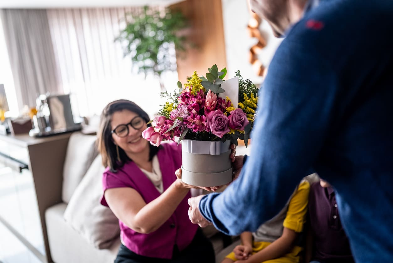 A smiling woman receiving a colorful bouquet of flowers from a man, symbolizing a loving gesture typical of Dia dos Namorados in Brazil.
