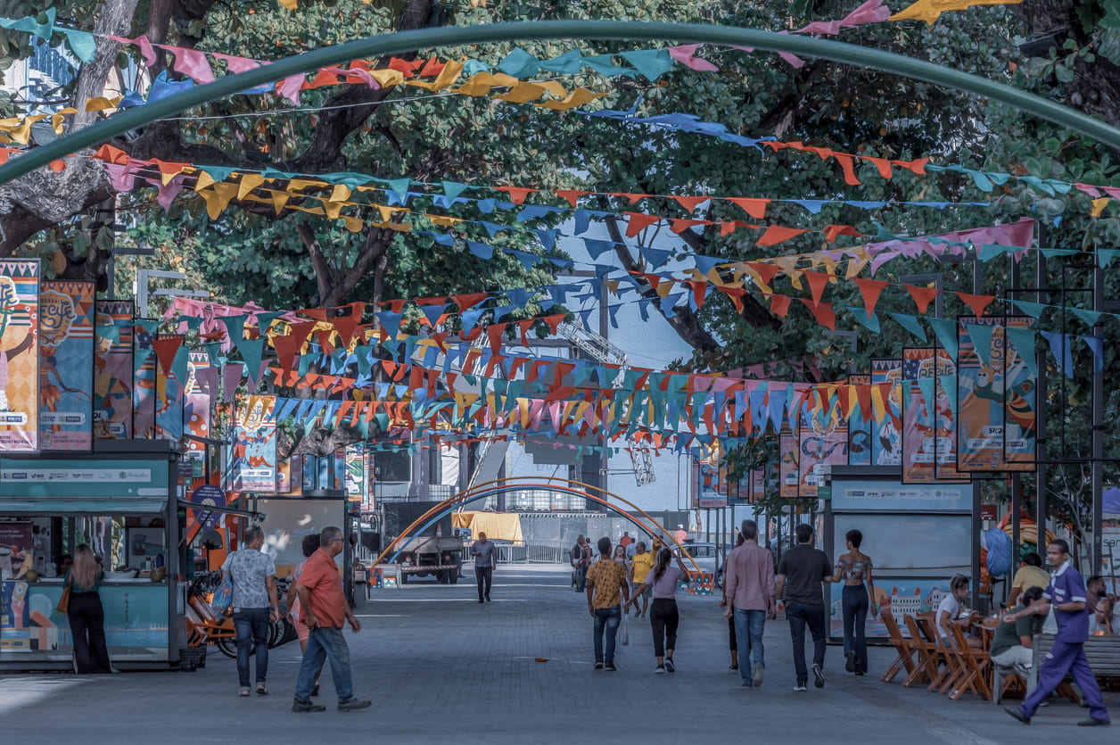 A decorated street with colorful flags and a few people strolling captures the calm atmosphere following the end of Carnival celebrations.