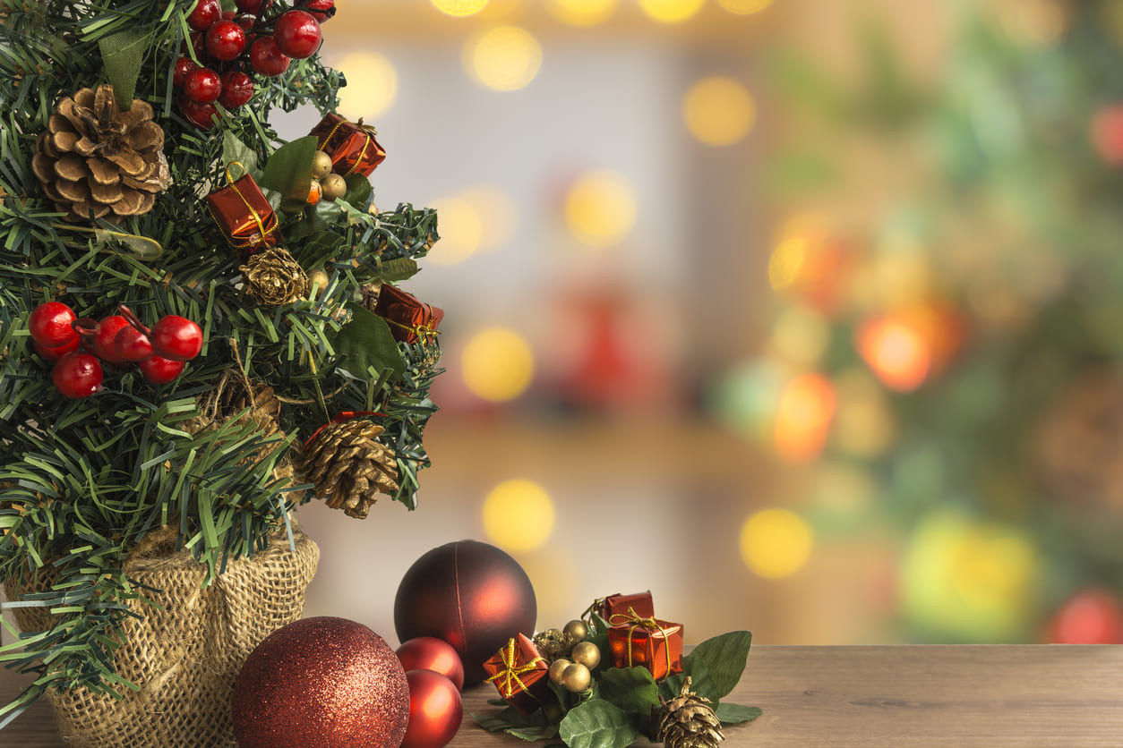 A close-up of a festive Christmas tree adorned with ornaments, pinecones, and gifts, creating a warm and cheerful holiday setting.