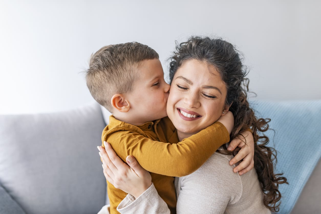 A joyful young boy hugging and kissing his smiling mother, capturing a tender and loving Mother's Day moment.