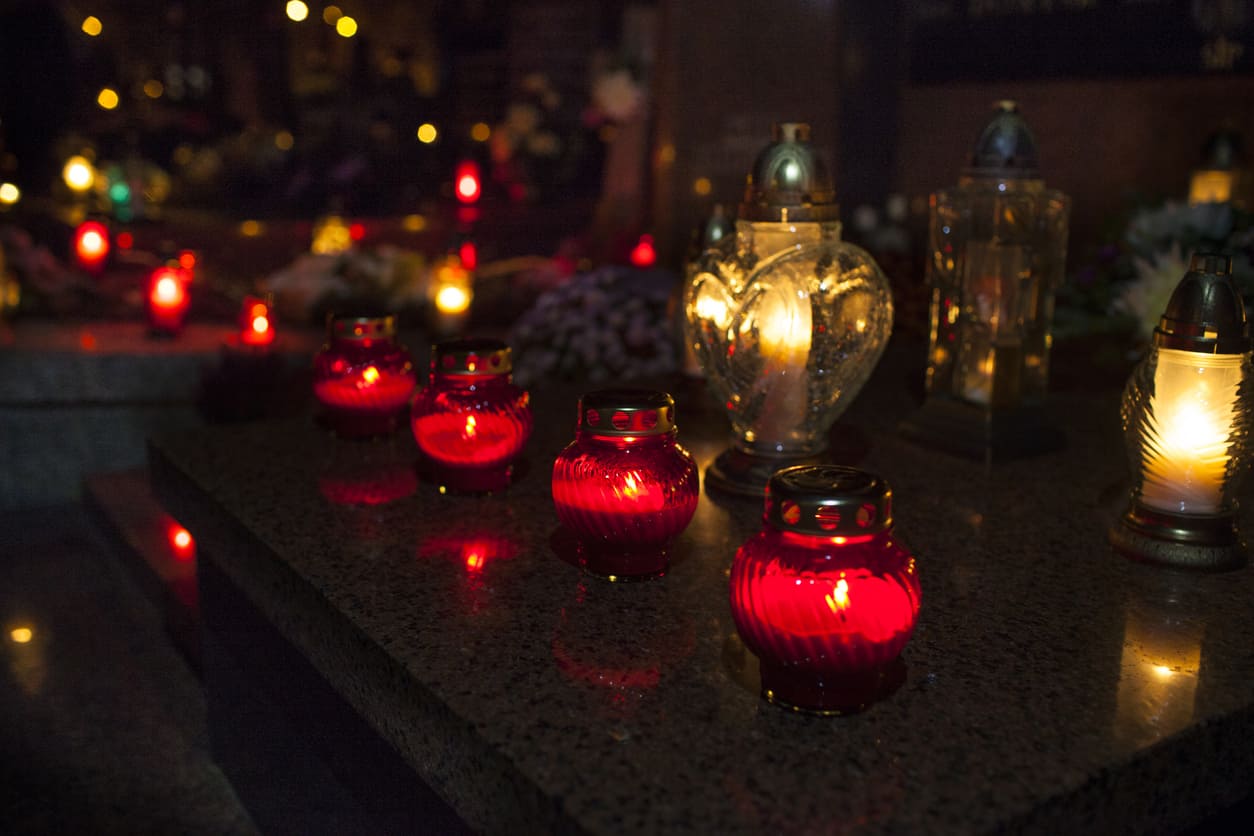 A serene scene of glowing candles placed on a tombstone, honoring departed loved ones on All Saints' Day.