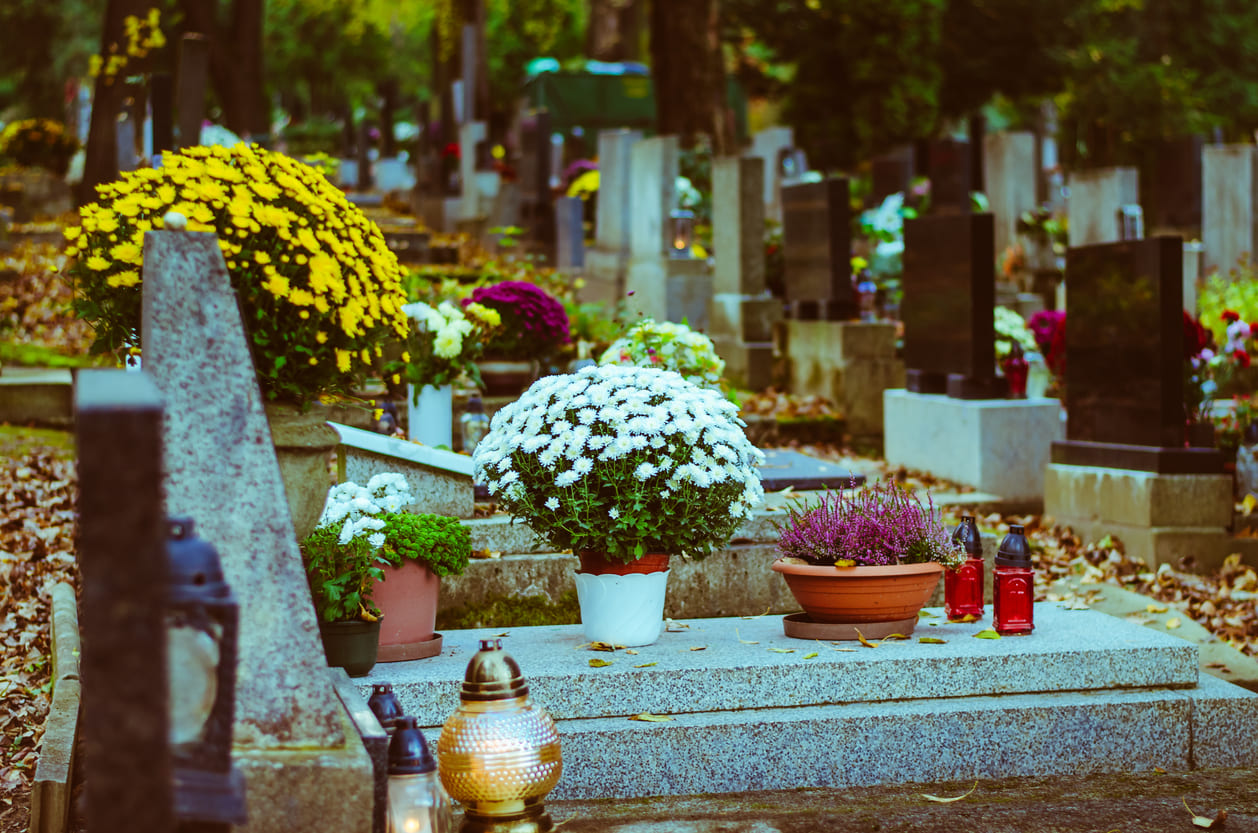 A serene cemetery with gravestones adorned with colorful flowers and glowing candles, symbolizing remembrance on All Souls' Day.