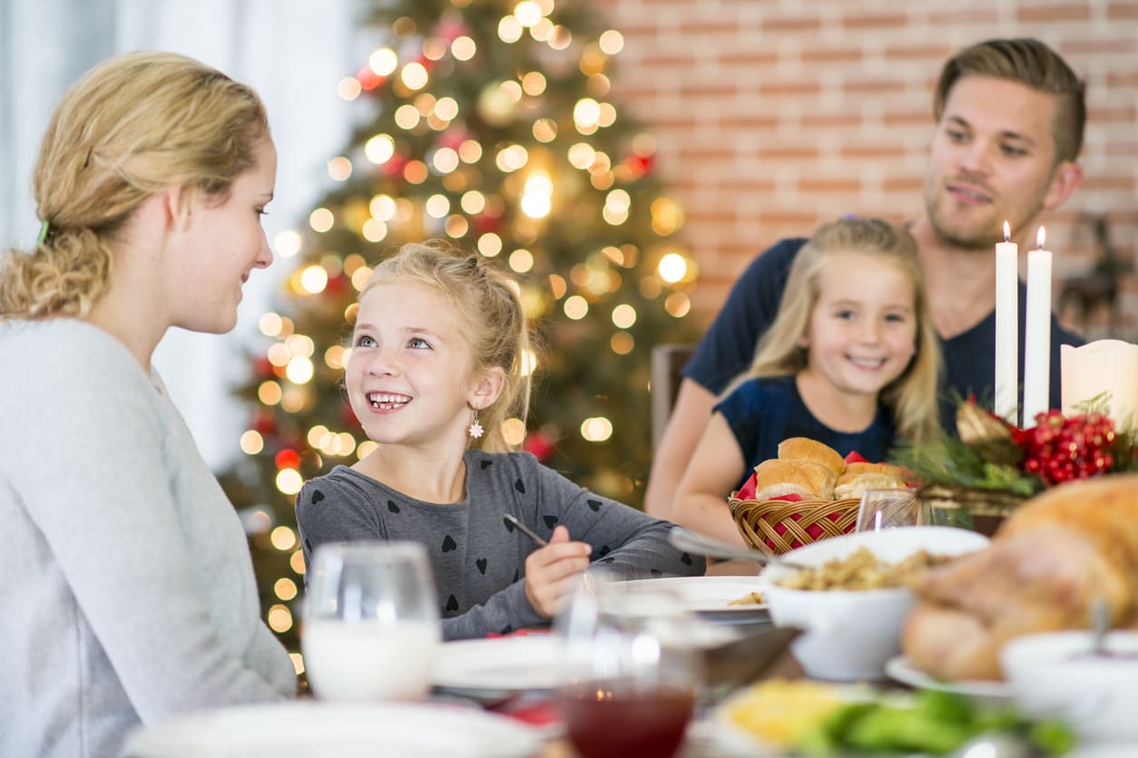 A family enjoying a warm and festive Christmas Eve dinner, surrounded by holiday decorations and glowing lights.