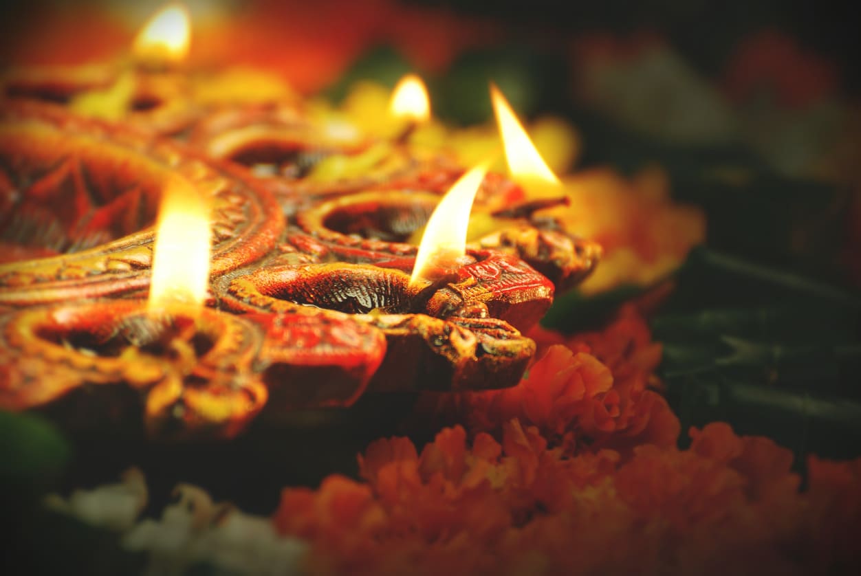 A beautifully decorated diya with flickering flames, surrounded by marigold flowers, capturing the warmth and spirituality of Diwali.