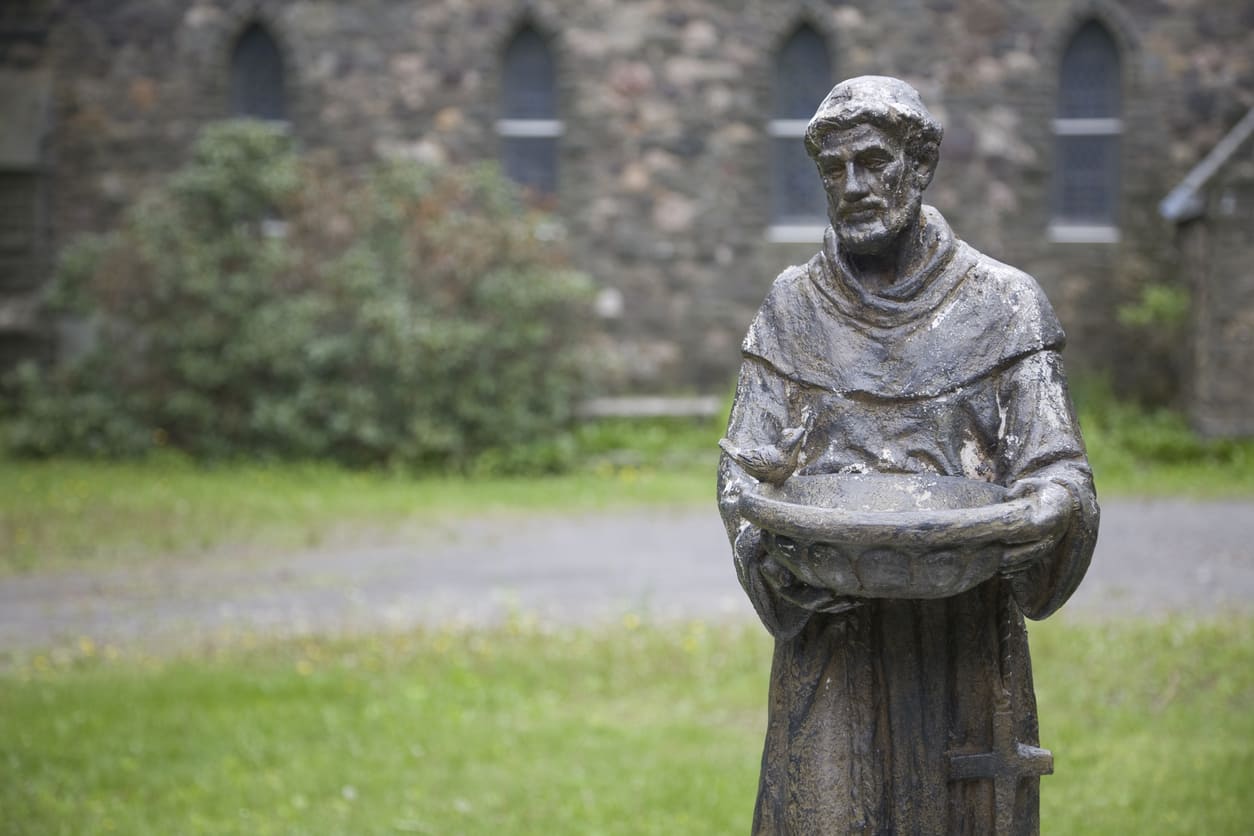 A weathered statue of St. Francis of Assisi, symbolizing his deep devotion to nature, animals, and a life of humility and compassion.