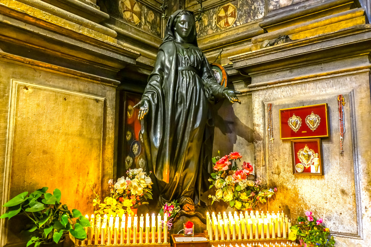 A beautifully adorned statue of the Virgin Mary, surrounded by candles and flowers, symbolizing devotion and purity on the Feast of the Immaculate Conception.