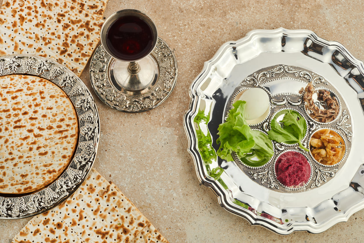 A traditional Passover Seder setup featuring a silver Seder plate with symbolic foods, matzah, and a cup of wine, representing the story of the Exodus.