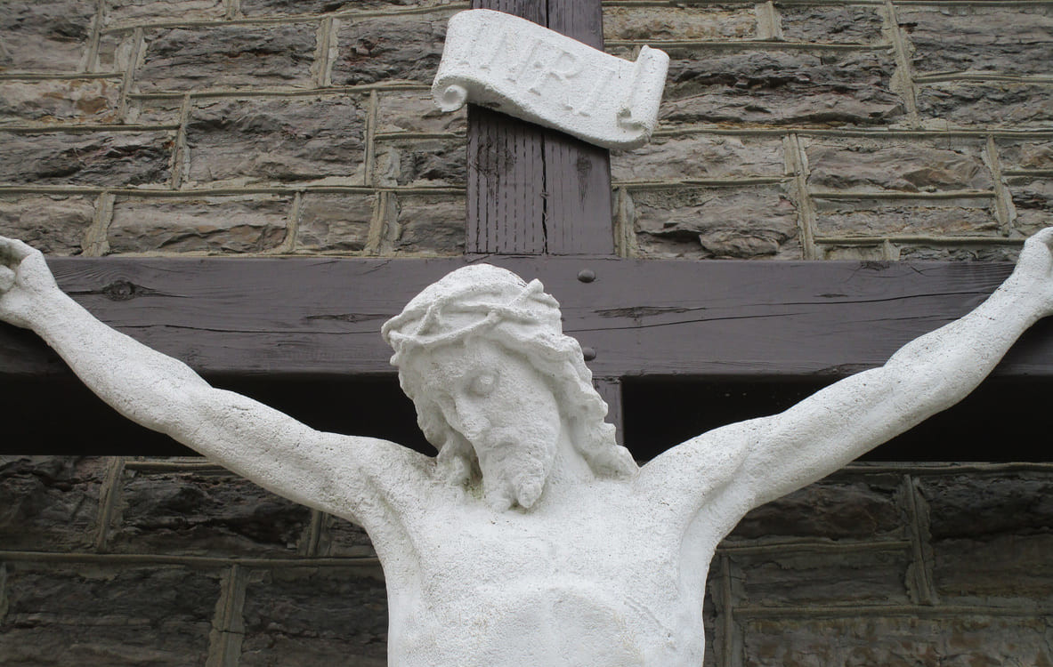 A statue of Jesus Christ on the cross set against a stone wall, symbolizing Good Friday.