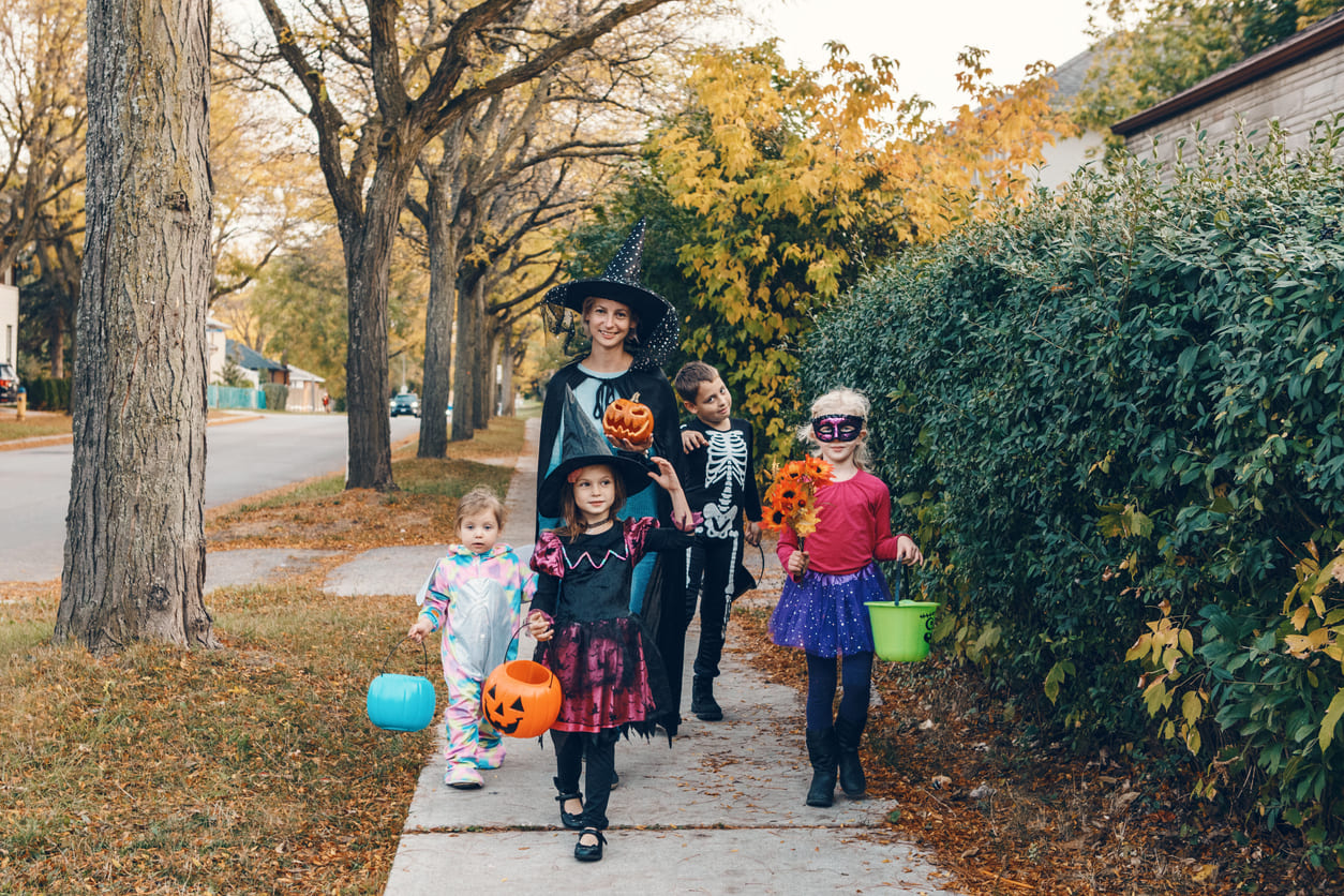 A group of children in Halloween costumes go trick-or-treating on a crisp autumn evening, embracing the festive spirit of Halloween in Canada.