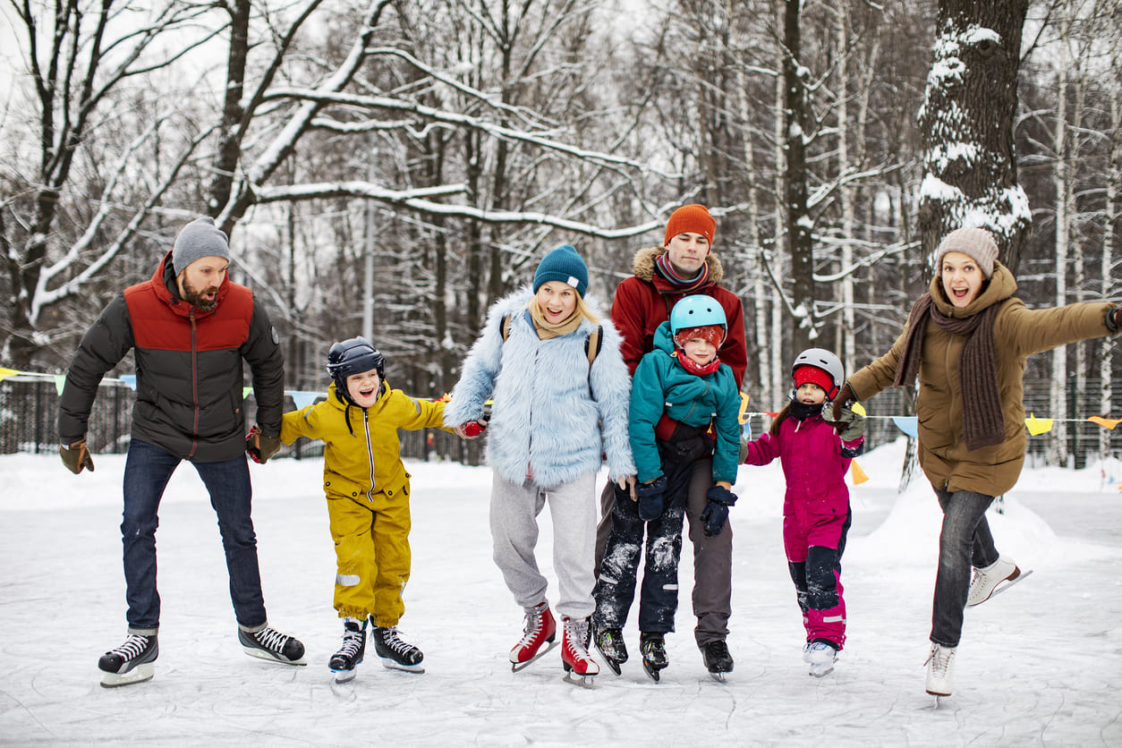 A cheerful group of friends and family enjoy ice skating outdoors, celebrating togetherness on Islander Day.