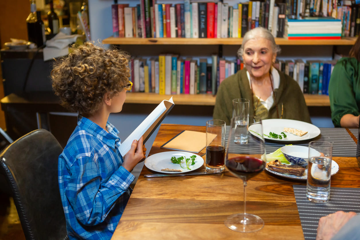 A family gathers around the table on the Last Day of Passover, with a child reading from the Haggadah, symbolizing the passing down of traditions and the celebration of freedom.