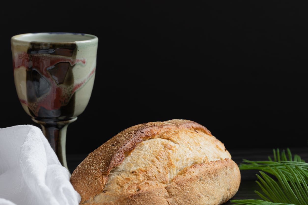 A solemn still life of bread and a chalice, symbolizing Holy Communion and the Last Supper on Maundy Thursday.