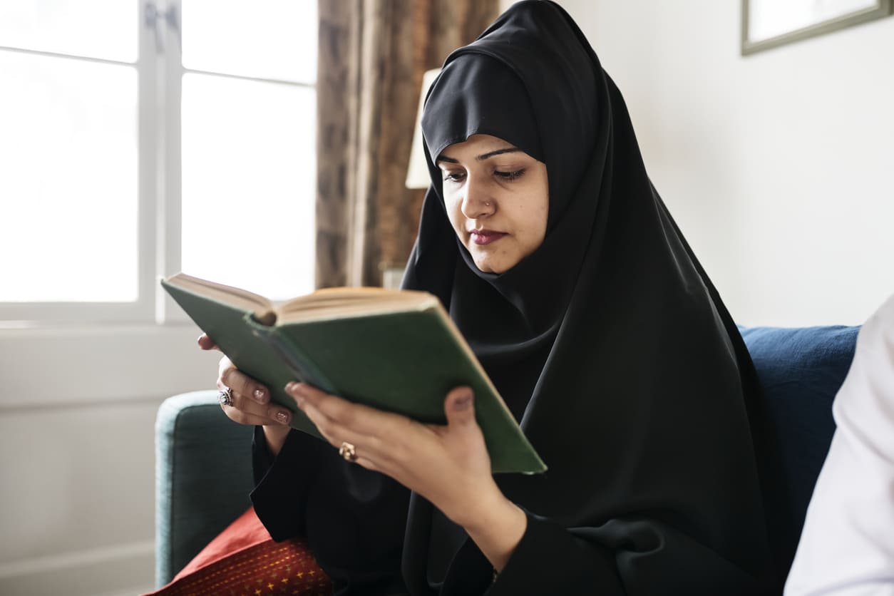A woman immersed in Quran recitation, embracing spiritual reflection and devotion during Milad Un Nabi.