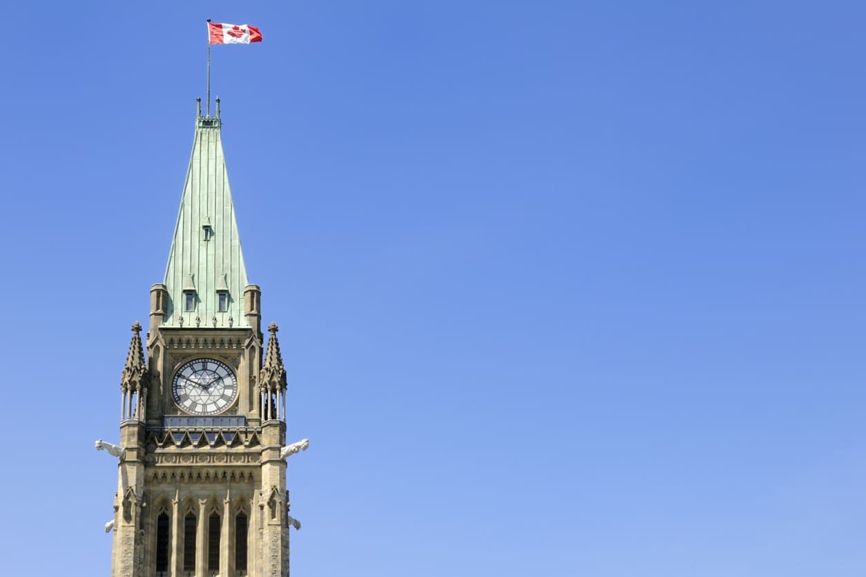 A striking view of the Canadian flag flying atop Parliament Hill's Peace Tower, representing national identity and heritage.