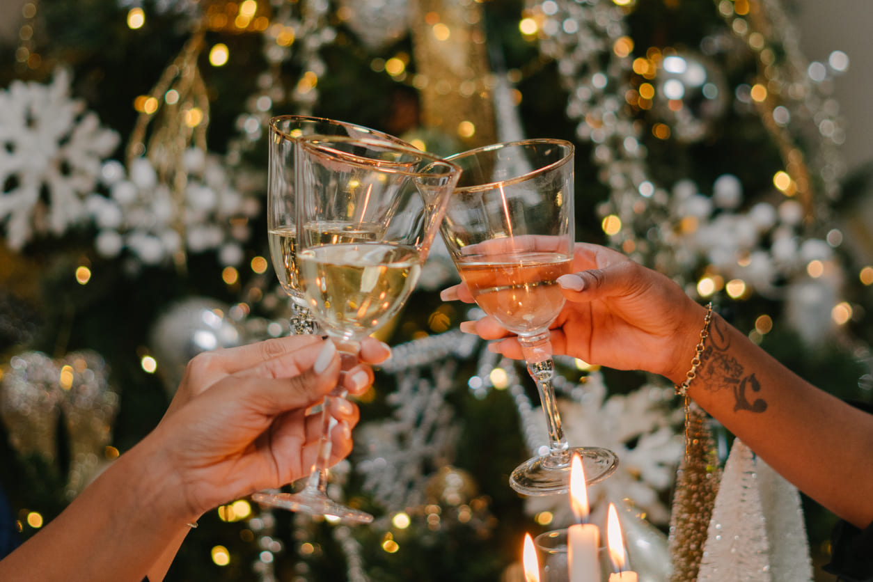 A close-up of hands clinking champagne glasses in a festive New Year's Eve celebration.