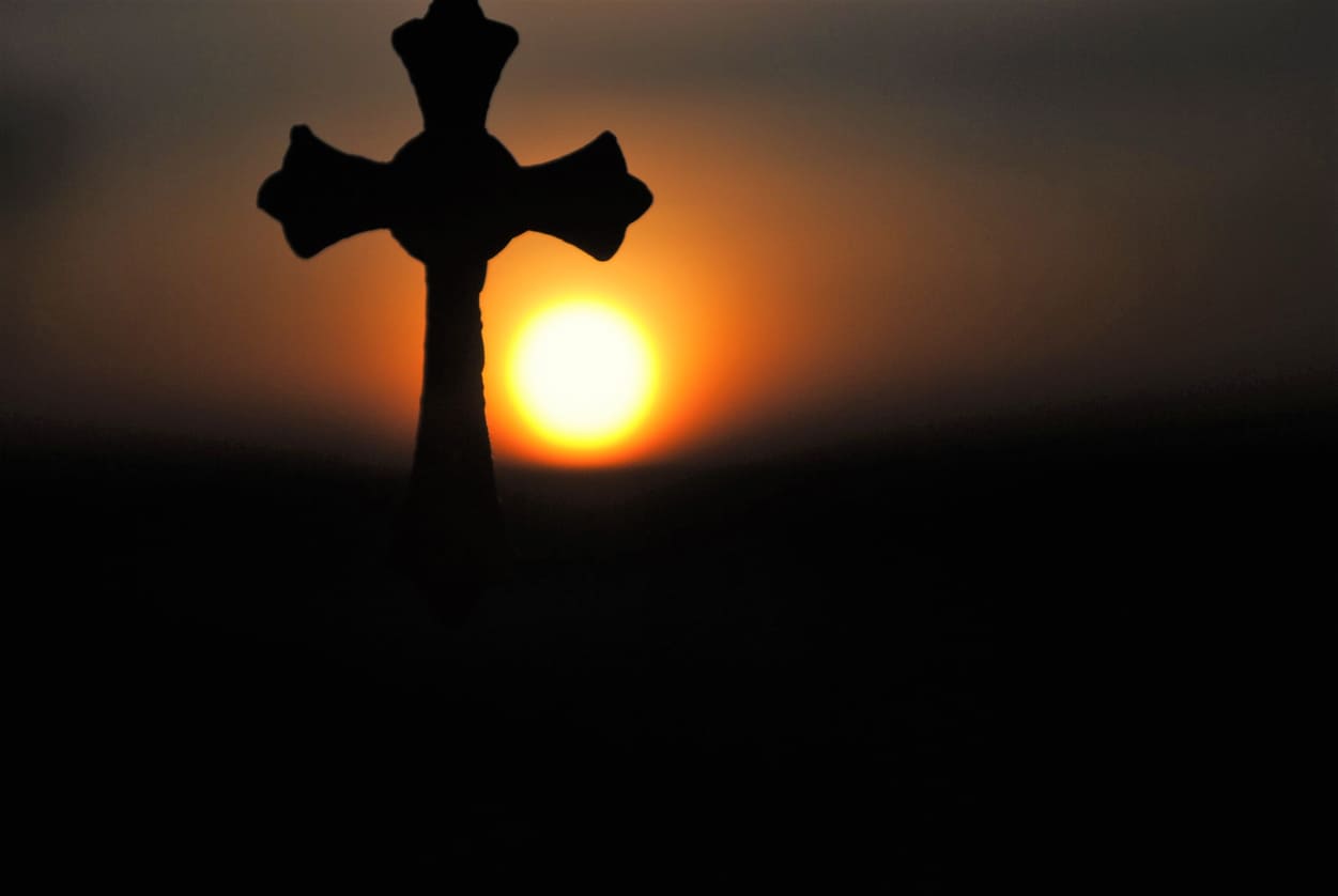 A silhouetted cross against a glowing sunset, symbolizing the solemnity and sacrifice of Orthodox Good Friday.