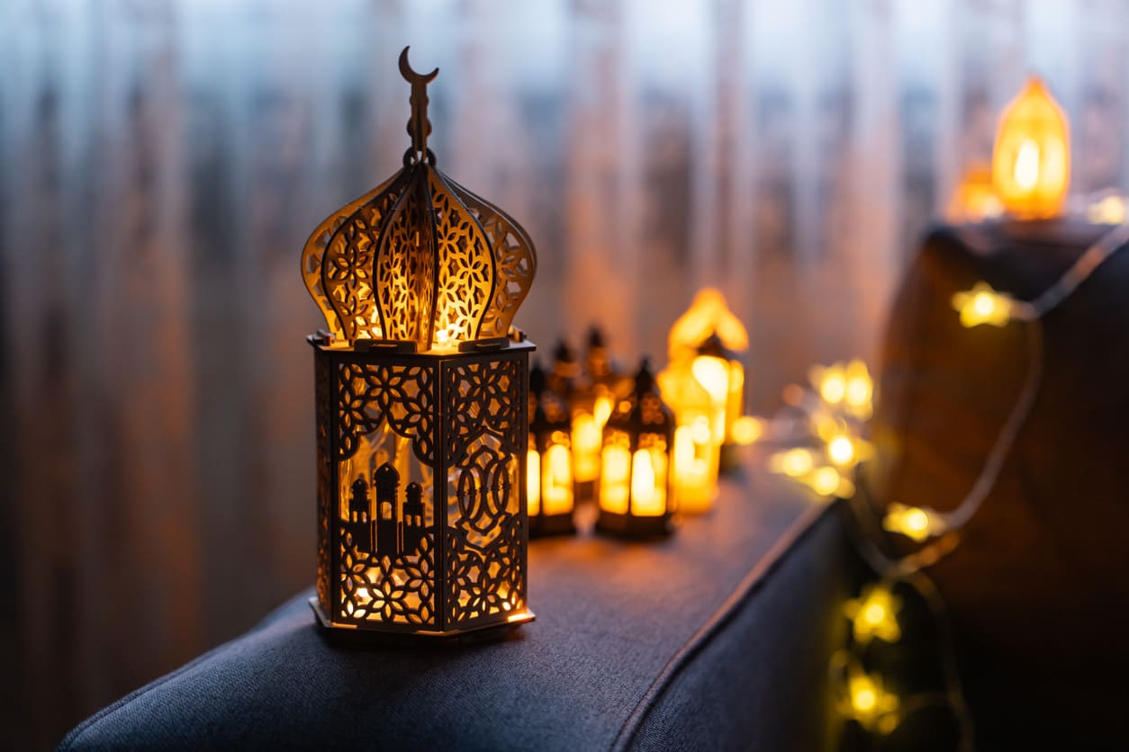 A beautifully designed Ramadan lantern glows warmly, surrounded by smaller lanterns and fairy lights, creating a peaceful and festive ambiance.