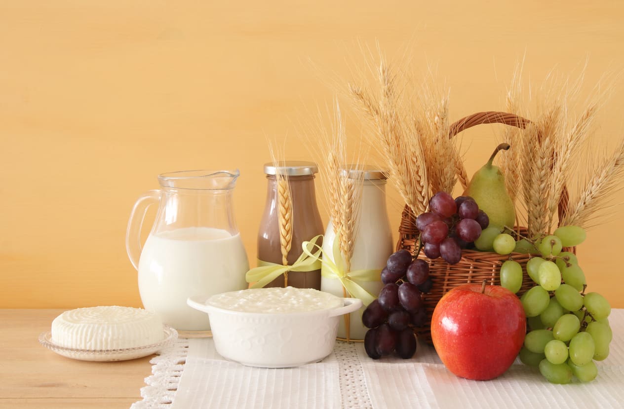 A Shavuot-themed display featuring dairy foods, wheat, and fresh fruits, symbolizing the holiday's connection to Torah, agriculture, and tradition.