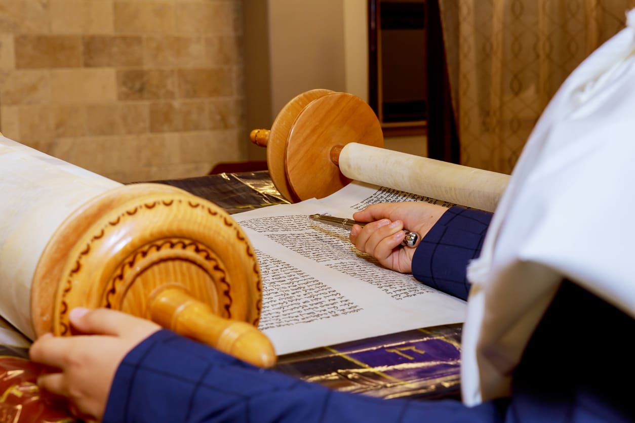 A Torah scroll being read with a yad, symbolizing the completion and renewal of the Torah cycle on Simchat Torah.