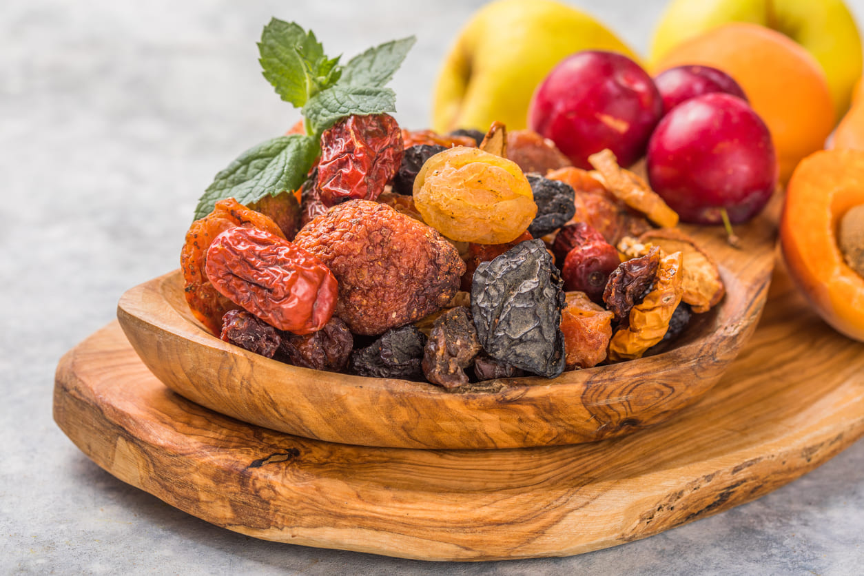 A wooden bowl filled with dried fruits, including apricots, raisins, and plums, symbolizing the Tu B'Shevat tradition of celebrating nature and renewal.