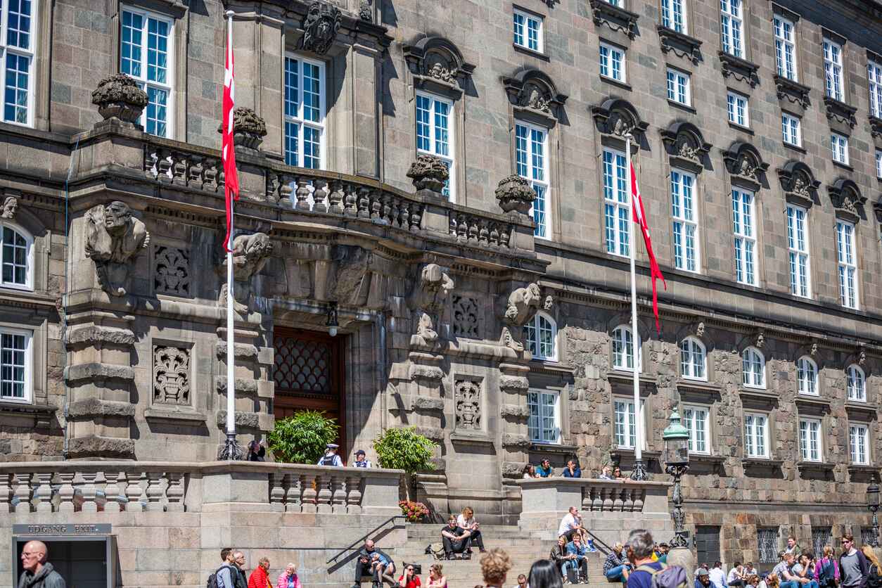 Christiansborg Palace in Copenhagen, where people gather under Danish flags to celebrate Constitution Day (Grundlovsdag) with national pride.
