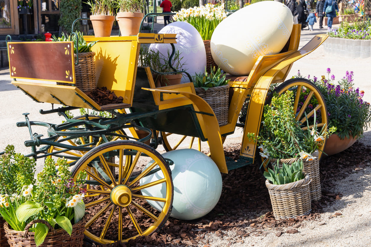 A festive Easter display in a Copenhagen park with a vintage carriage, oversized eggs, and spring flowers.